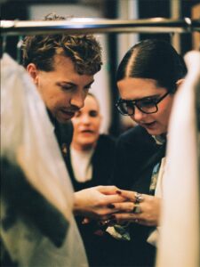 Two people looking closely at jewellery between garment rails inside the new Fortitude Valley studio