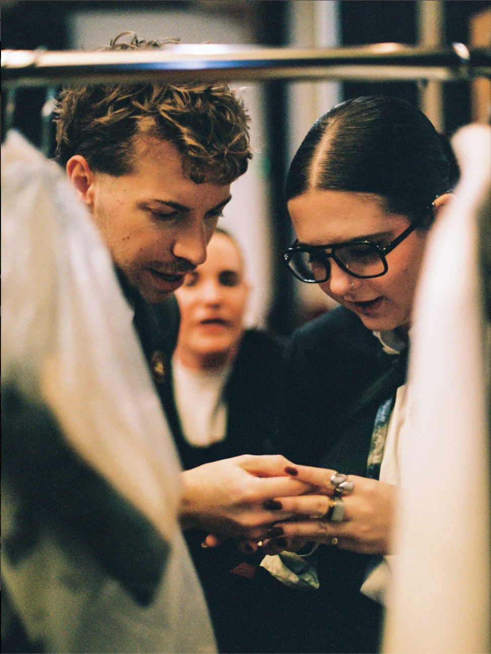 Two people looking closely at jewellery between garment rails inside the new Fortitude Valley studio