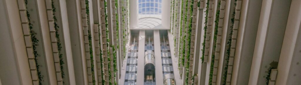InterContinental Brisbane renovation story: hotel atrium looking up to a glass skylight, with glass lifts and greenery