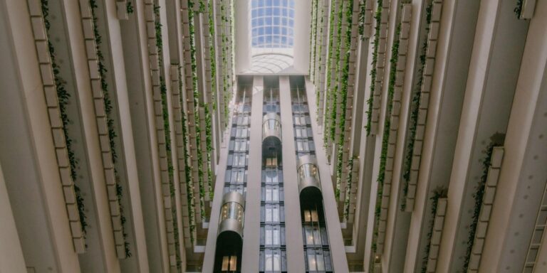 InterContinental Brisbane renovation story: hotel atrium looking up to a glass skylight, with glass lifts and greenery